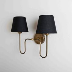 two black lamps on a white wall with one light on the opposite side and another lamp on the right