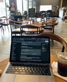 an open laptop computer sitting on top of a table next to a cup of coffee