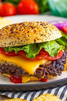 a cheeseburger with lettuce and tomatoes on a plate next to chips