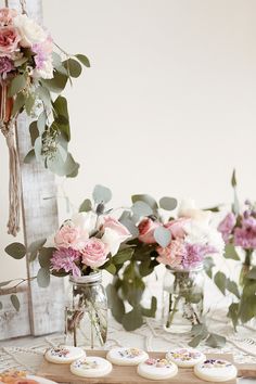 flowers in vases and cookies on a table