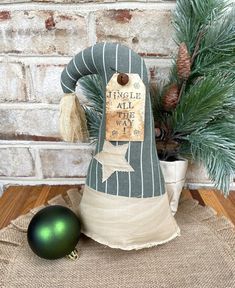 a green christmas ornament sitting on top of a table next to a pine tree