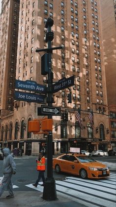 people crossing the street at an intersection in new york city, with tall buildings behind them