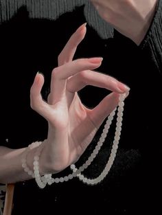 a woman with her hands in the shape of a hand holding a strand of pearls