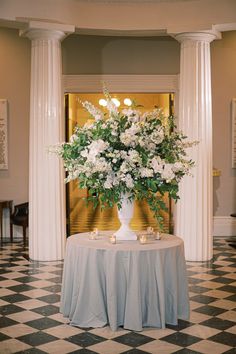 a vase filled with white flowers sitting on top of a table next to two candles