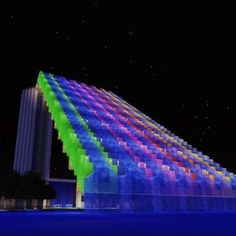 a large building lit up at night with colorful lights on it's side and the sky in the background