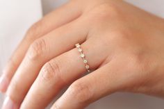 a woman's hand wearing a gold ring with three small stones on the band