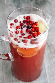 a pitcher filled with liquid and cranberries on top of a table