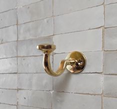 a white brick wall with a gold hook on it