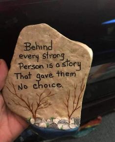 someone is holding up a rock that says, behind every strong person is a story that gave them no choice