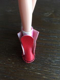 a doll's feet in a red slipper on top of a wooden table