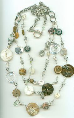 a long necklace with various buttons and chains hanging from it's center, on a white surface