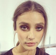 a close up of a woman with makeup on her face and hair in pony tail