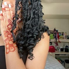 a woman with her hands on her face covered in hendi tattoos, sitting on a bed