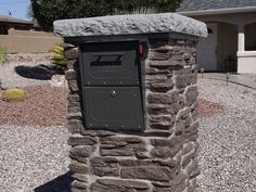 a mailbox in front of a house with gravel and rocks on the ground next to it