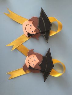 two paper cut out figures with graduation caps and gowns on top of each other