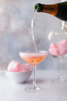 a bottle of champagne being poured into a wine glass filled with ice and pink jello