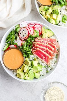 two white bowls filled with different types of food on top of a table next to each other