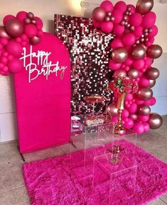 pink and gold balloons are on display in front of a birthday backdrop with an arch