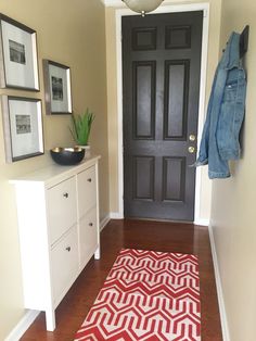 a hallway with a black door and red rug