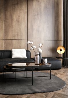 a modern living room with wood paneling and black sofas, coffee table and vase