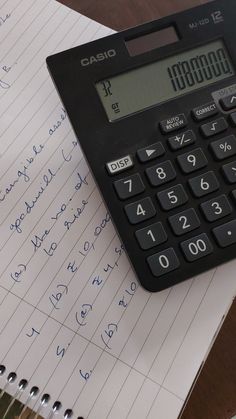 a calculator sitting on top of a piece of paper next to a notebook