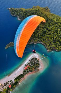 an aerial view of a parasailer gliding over the water in front of a small island