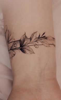 a woman's foot with a feather and flower tattoo on the left side of her ankle