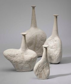 three white vases sitting next to each other on a gray surface with writing on them