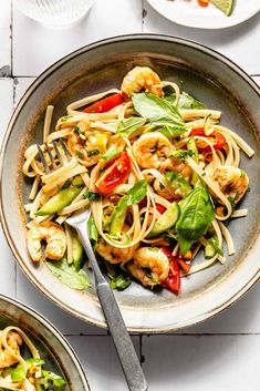 two bowls filled with pasta and shrimp on top of a table