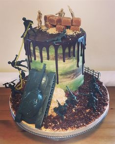 a birthday cake decorated with toy soldiers and chocolate icing on a wooden table top