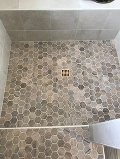 a tiled shower stall with a drain in the middle and tile on the floor next to it