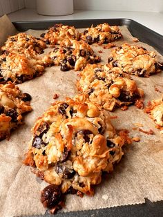 an uncooked batch of cookies sitting on top of a cookie sheet with raisins and cranberries