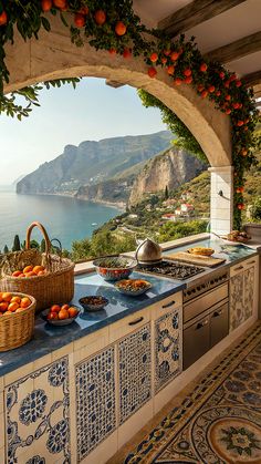 an outdoor kitchen with oranges and other foods on the counter, overlooking the ocean