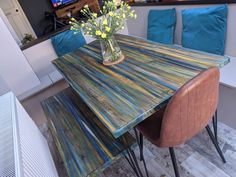 a wooden table with blue cushions and flowers in a vase