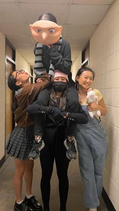 three people standing in a hallway with one person wearing a mask and the other holding a stuffed animal