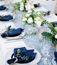 the table is set with blue napkins and place settings for an elegant dinner party