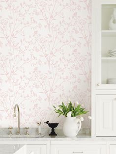 a white vase sitting on top of a kitchen counter next to a wallpapered wall