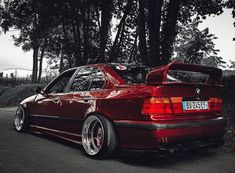 a red car parked in front of some trees