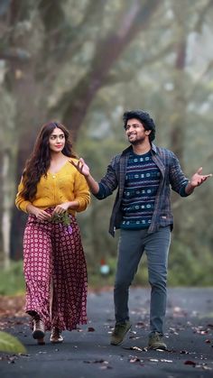 a man and woman walking down a road holding hands