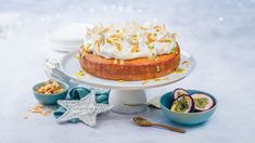 a cake sitting on top of a white plate next to bowls of fruit and nuts