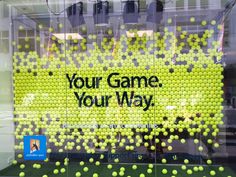 a display case with tennis balls in it and the words your game, your way