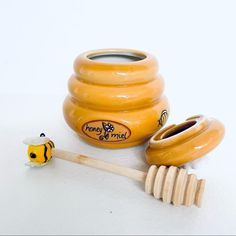 a honey pot with a wooden stick next to it and a toy bee on the ground