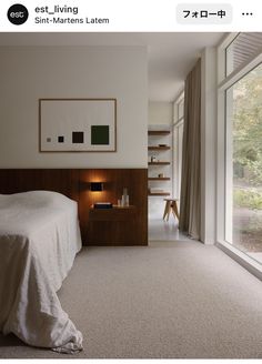 a white bed sitting next to a window in a bedroom under a framed picture on the wall