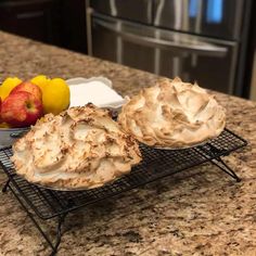 two pies sitting on top of a cooling rack next to some apples and lemons