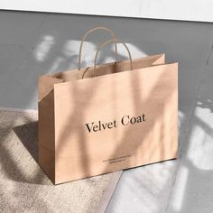 a brown paper bag sitting on top of a white rug next to a building with the words velvet coat printed on it