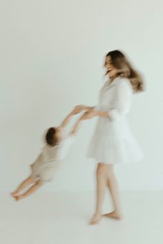 a mother and her child playing with each other in the white room, blurry image