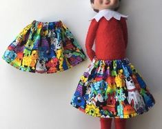 an elf doll is wearing a colorful skirt and red shirt with cartoon characters on it