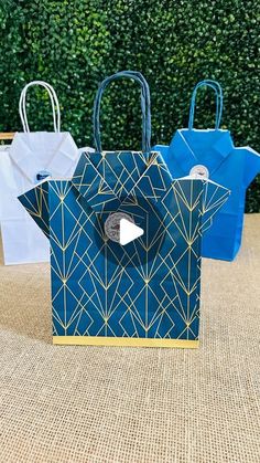 three blue and white paper bags sitting on top of a brown table next to each other