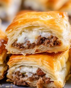 some meat and cheese pastries are stacked on top of each other, ready to be eaten