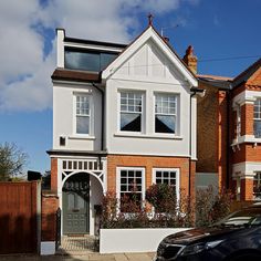 a car is parked in front of a large house with two story windows and white trim